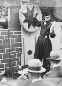 876694 Portret van een medewerker van het Franciscus Liefdewerk in Volendammer klederdracht, bij het rad van fortuin op ...